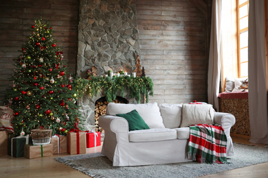 Festive interior with comfortable sofa and decorated Christmas tree