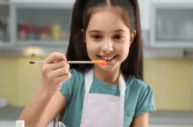 Photo of Cute little girl making homemade slime toy at table in kitchen