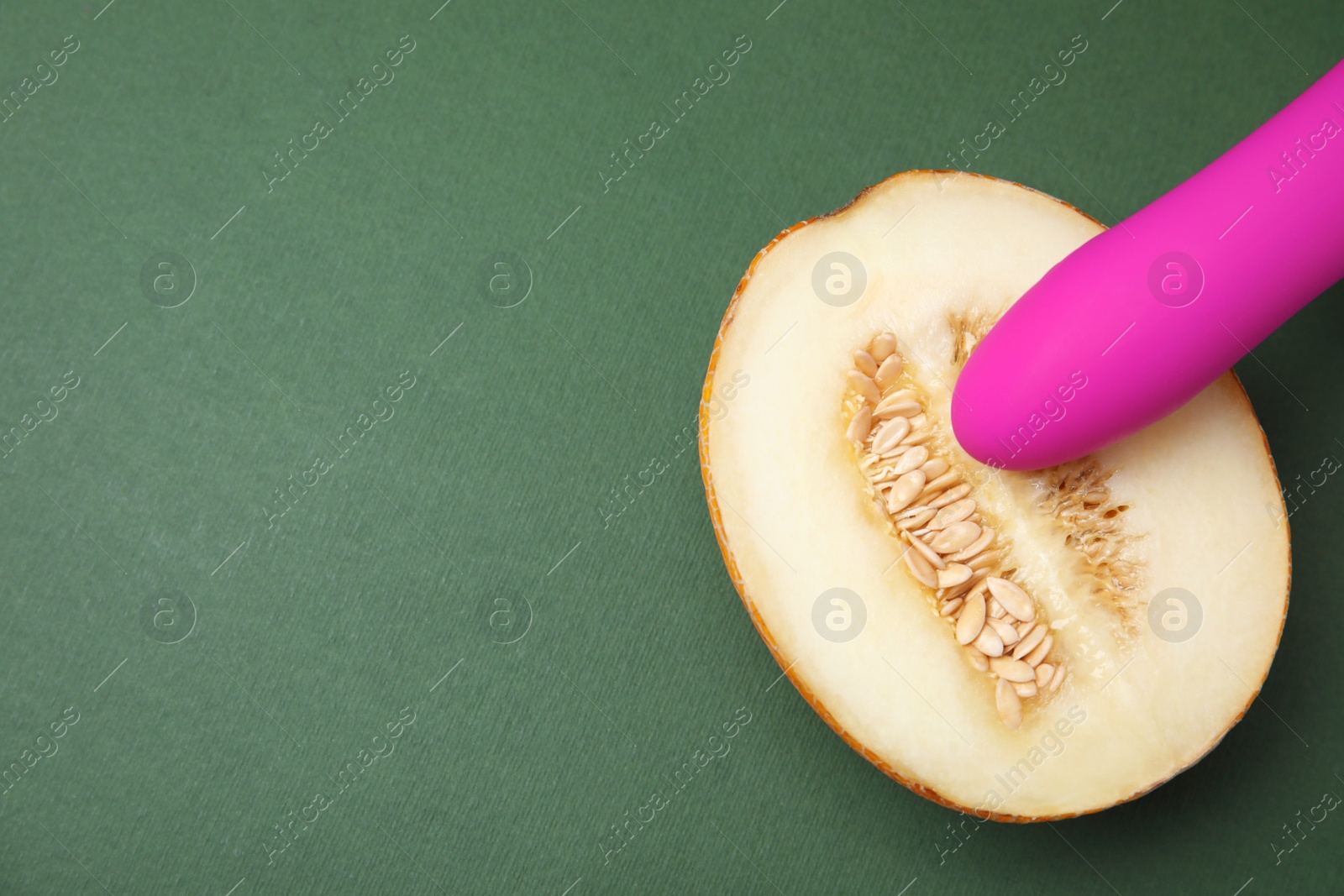 Photo of Half of melon and purple vibrator on dark grey background, flat lay with space for text. Sex concept