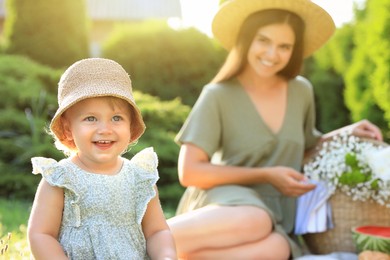 Photo of Mother and her daughter having picnic in garden, focus on baby
