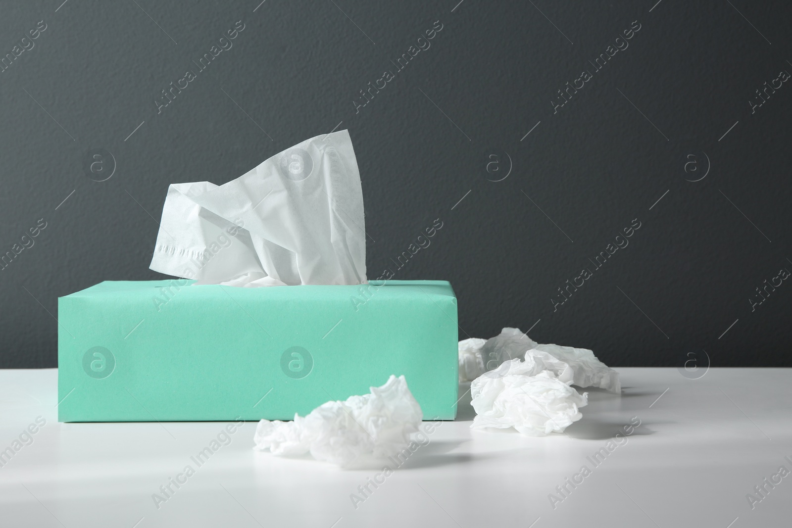 Photo of Used paper tissues and box on white table