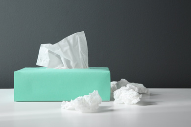 Photo of Used paper tissues and box on white table