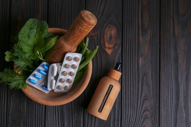 Mortar with fresh green herbs, extract and pills on wooden table, flat lay. Space for text