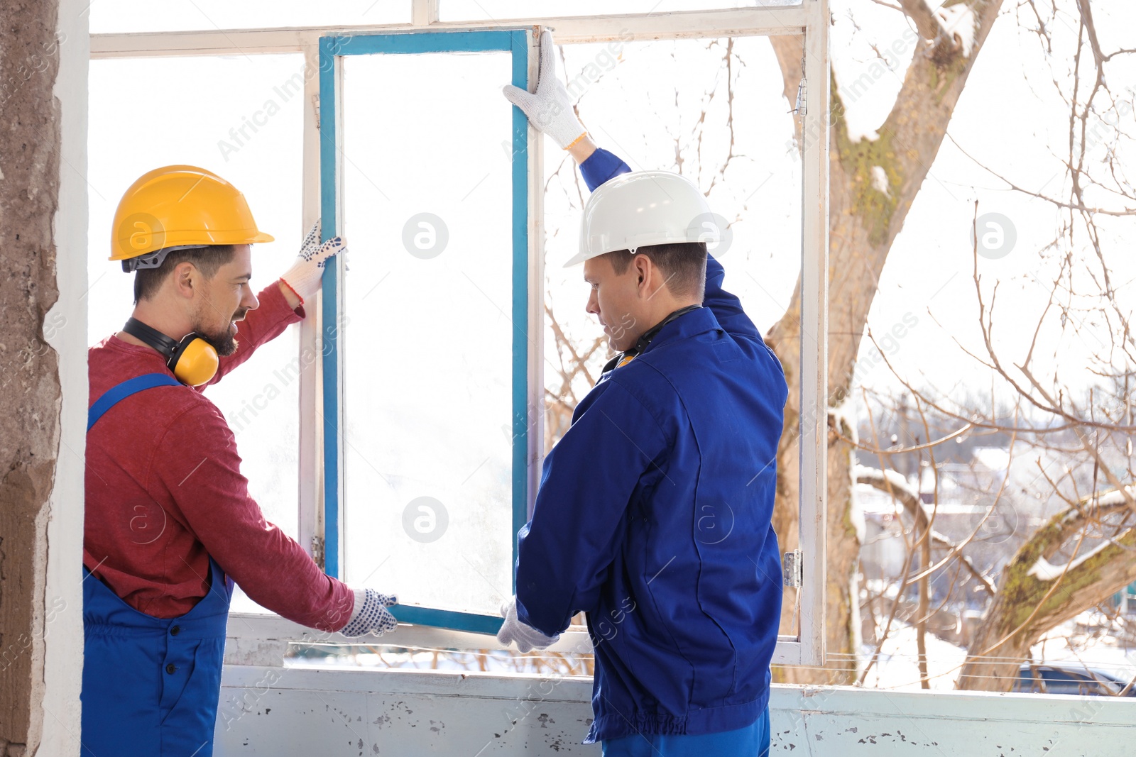 Photo of Workers in uniform dismantling old window indoors