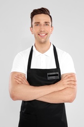 Photo of Portrait of handsome waiter in apron on light background