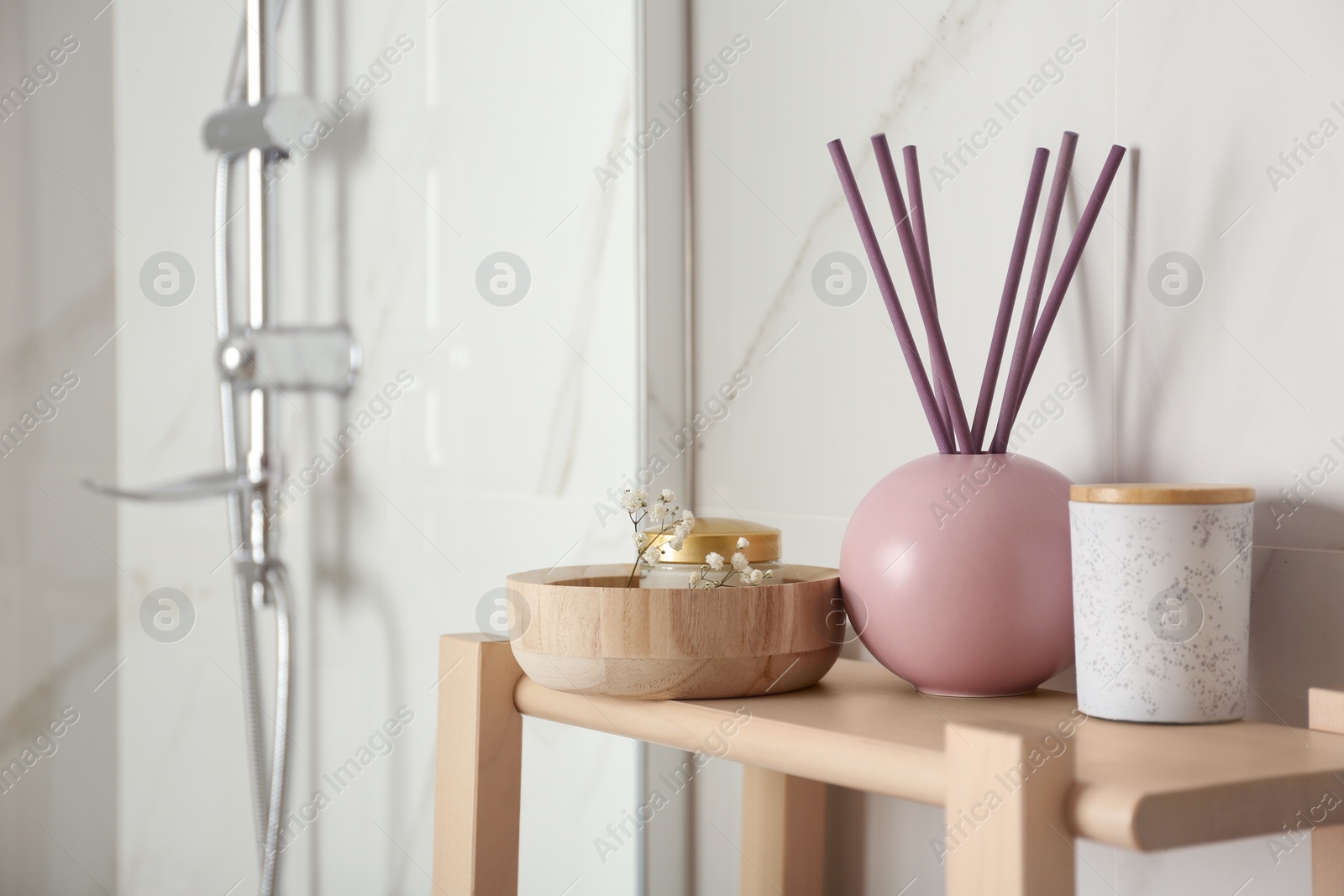 Photo of Shelving unit with reed air freshener in bathroom interior