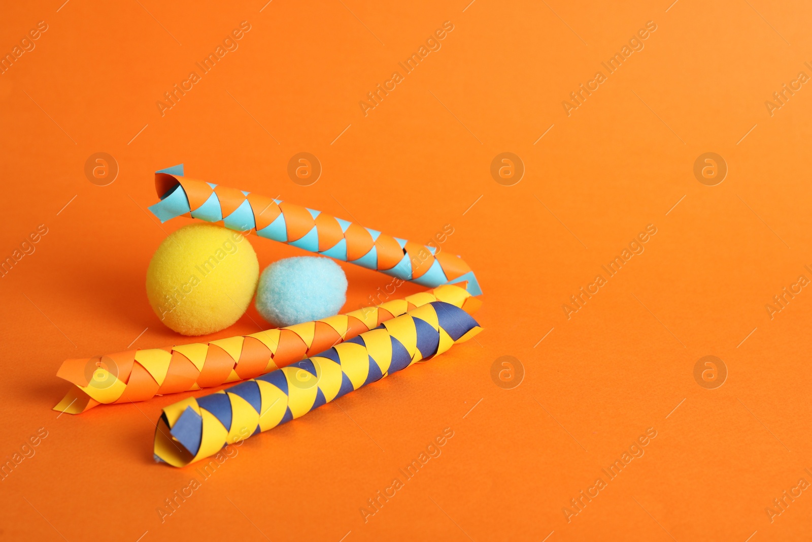 Photo of Chinese finger traps and clown noses on orange background, space for text