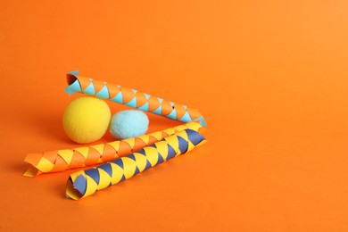 Chinese finger traps and clown noses on orange background, space for text