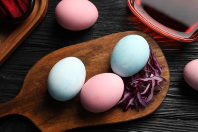 Photo of Naturally painted Easter eggs on black wooden table, flat lay. Red cabbage used for coloring