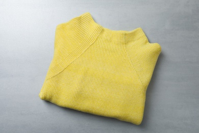 Yellow warm sweater on light grey table, top view
