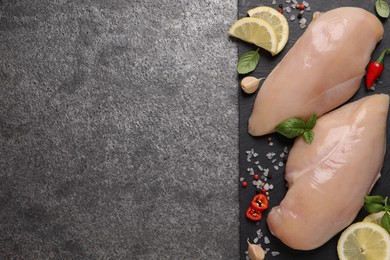 Raw chicken breasts and ingredients on grey table, top view. Space for text