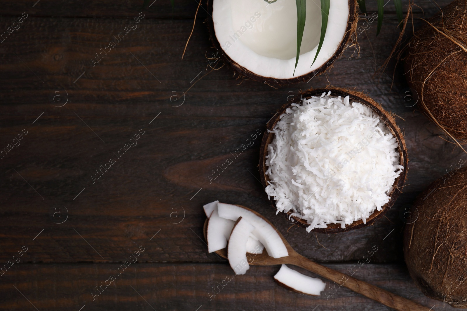 Photo of Coconut flakes, spoon and nuts on wooden table, flat lay. Space for text