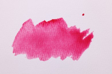 Photo of Blot of pink watercolor paint on white paper, top view