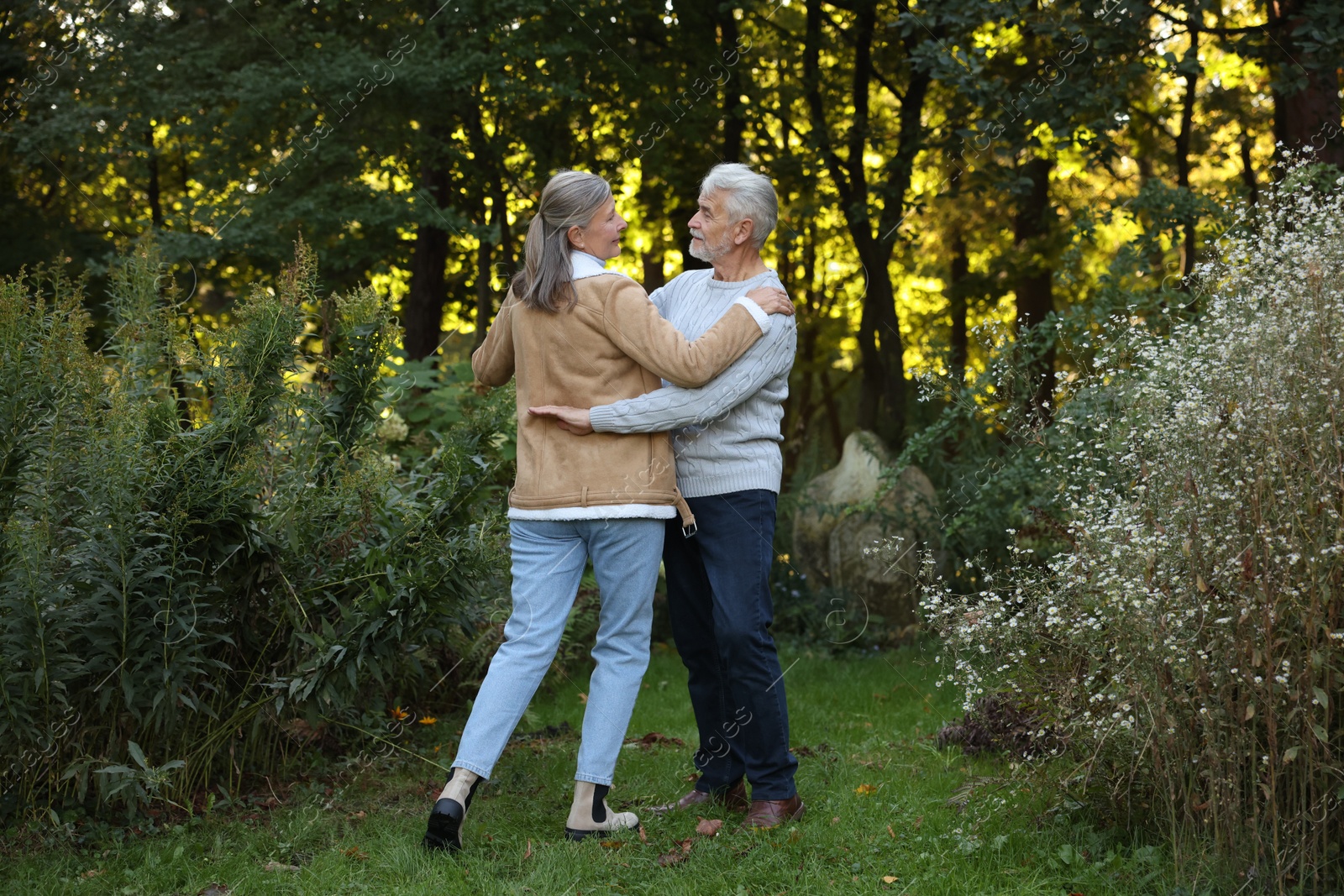 Photo of Affectionate senior couple dancing together in park. Romantic date