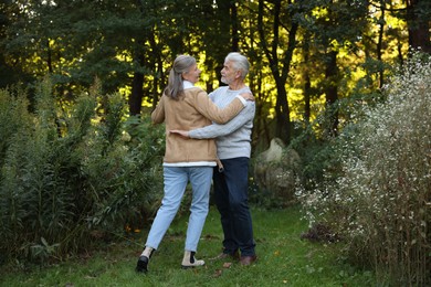 Affectionate senior couple dancing together in park. Romantic date