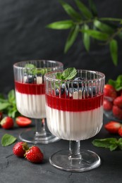 Photo of Delicious panna cotta with fruit coulis and fresh berries on dark grey table