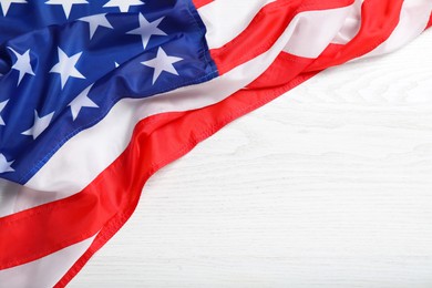 Photo of American flag on white wooden table, top view. Space for text