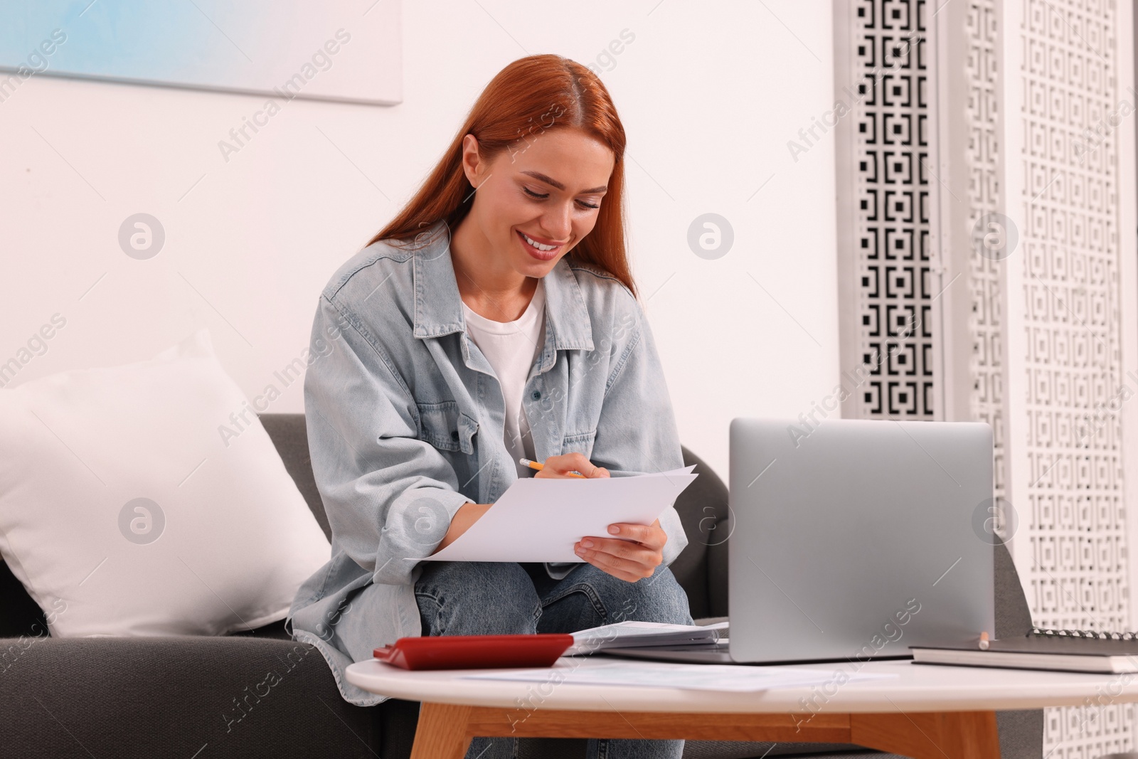 Photo of Woman calculating taxes at table in living room