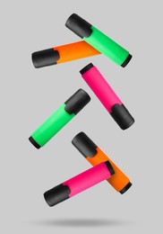 Image of Green, orange and pink markers falling on light background