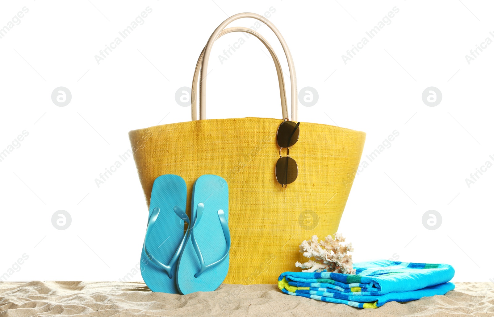 Photo of Stylish yellow bag and beach accessories on sand against white background