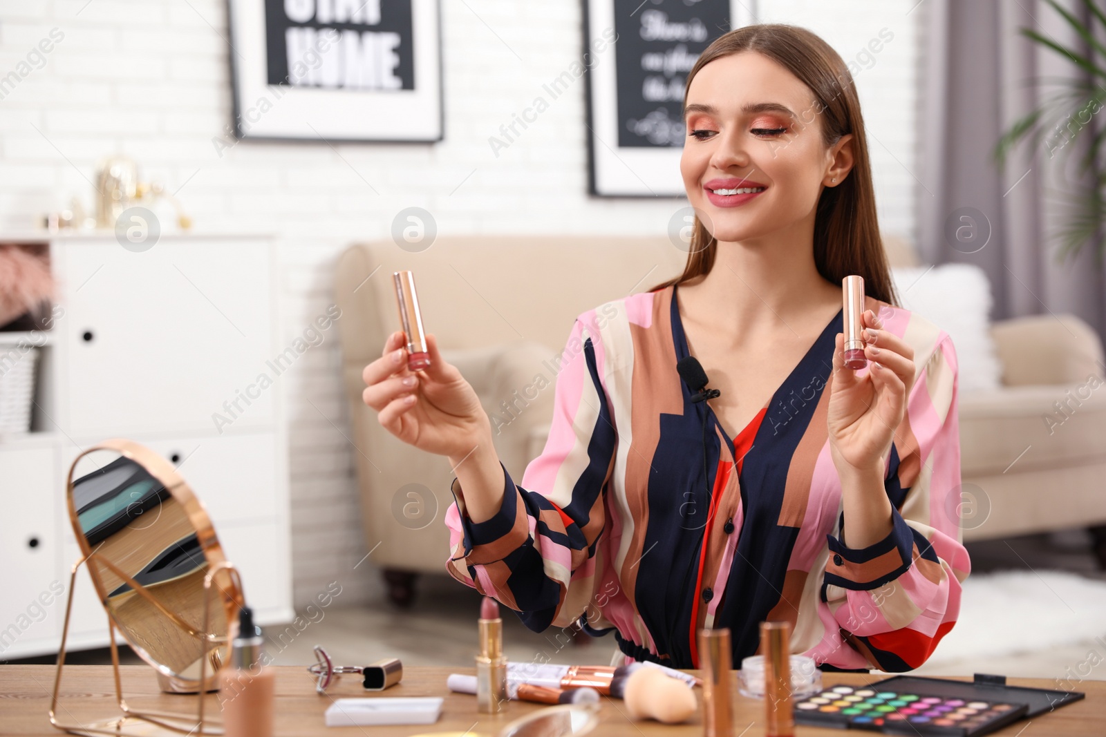 Photo of Young beauty blogger showing lipsticks at home