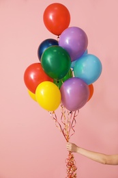 Photo of Woman holding bunch of bright balloons on color background, closeup. Celebration time