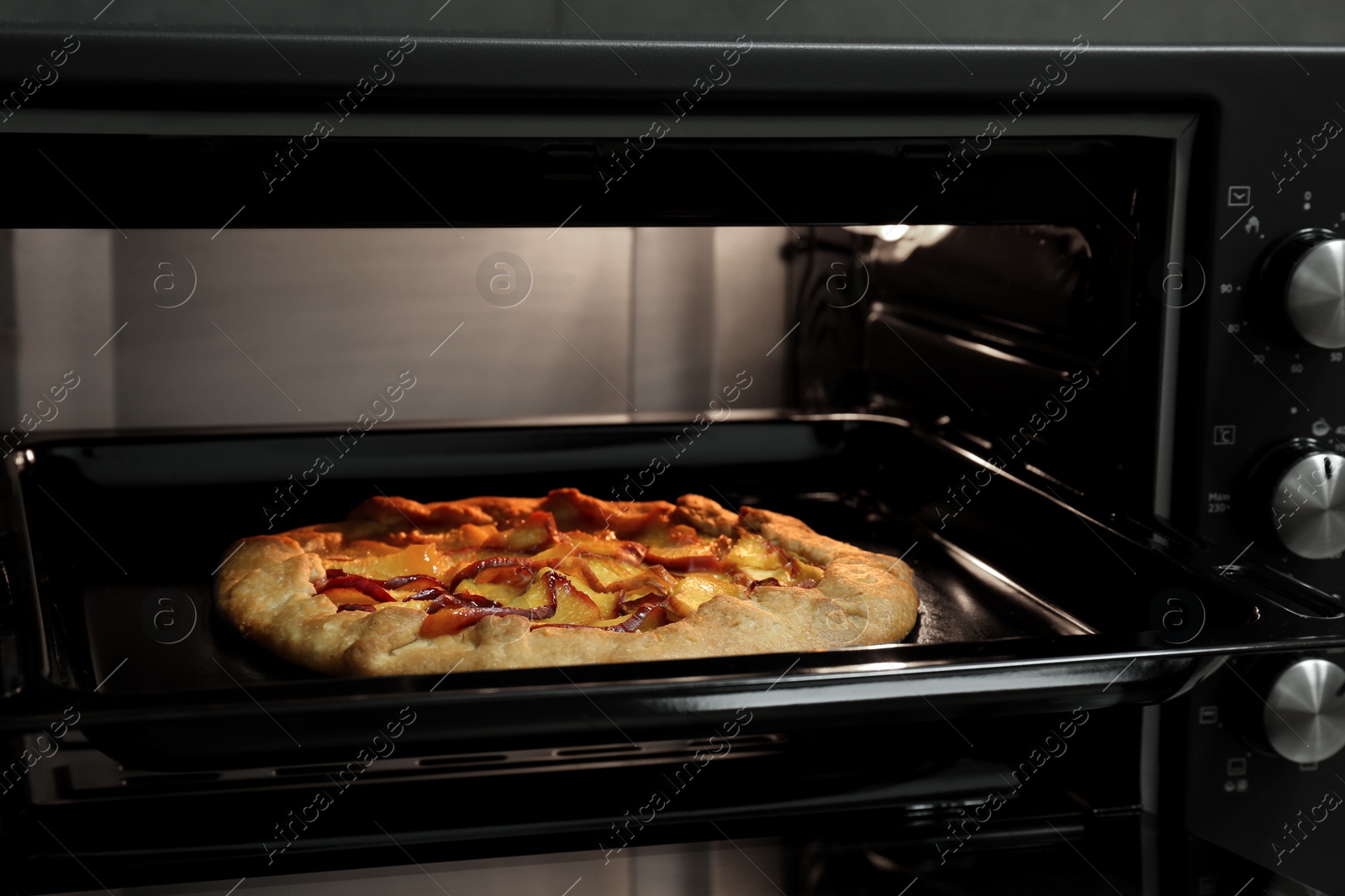 Photo of Baking delicious pie in electric oven, closeup