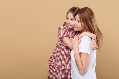 Photo of Portrait of mother and her cute daughter on beige background. Space for text