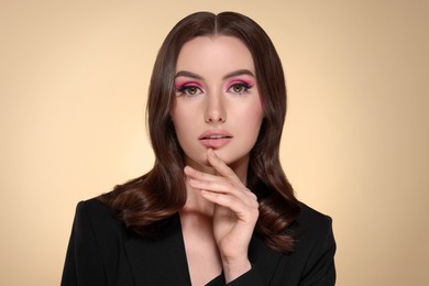 Photo of Portrait of beautiful young woman with makeup and gorgeous hair styling on beige background