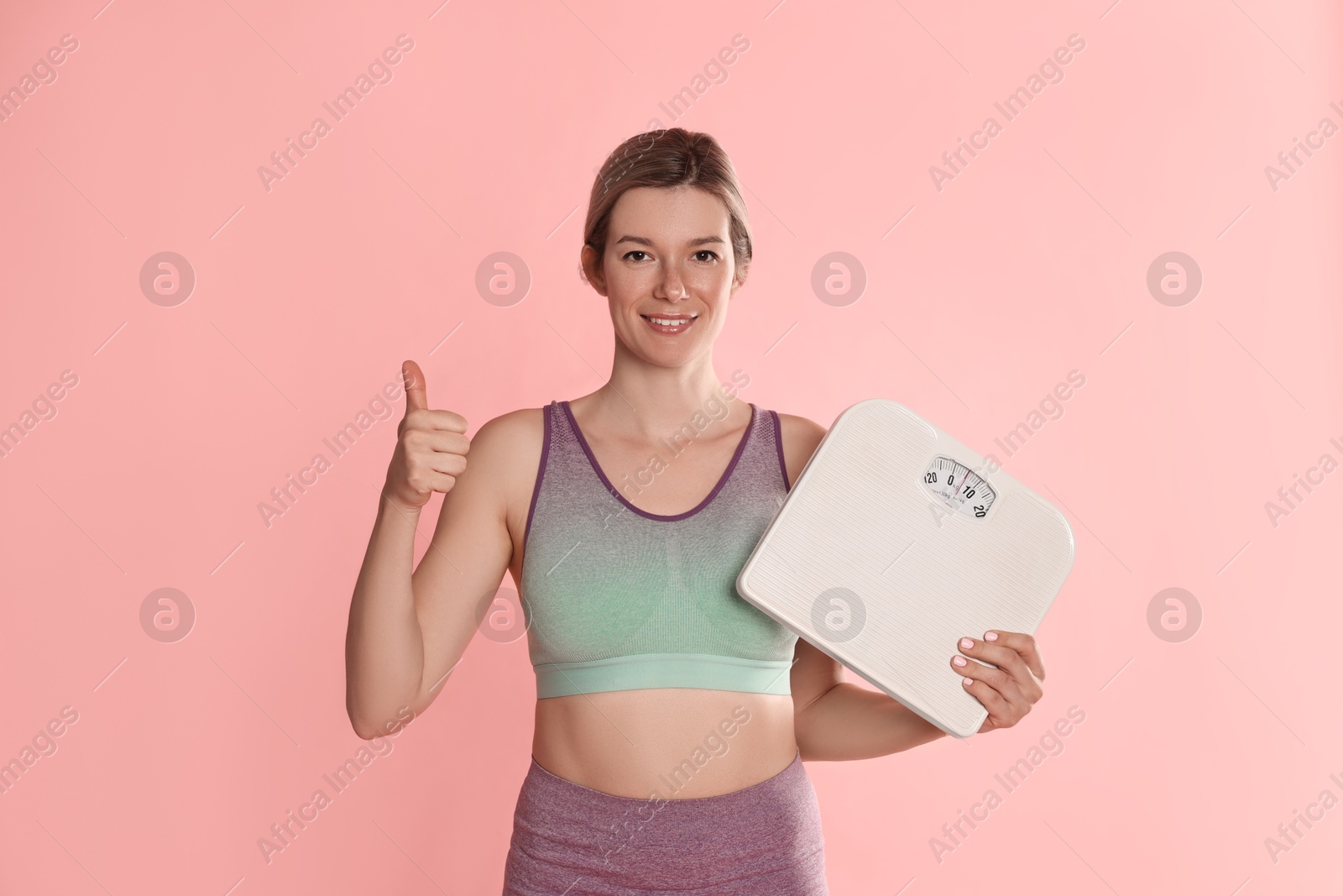 Photo of Beautiful woman with scales showing thumbs up on pink background
