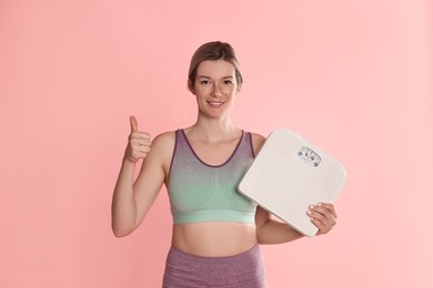 Beautiful woman with scales showing thumbs up on pink background