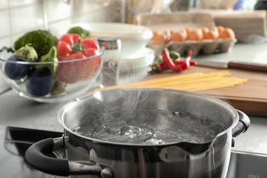 Pot with boiling water on electric stove in kitchen, closeup