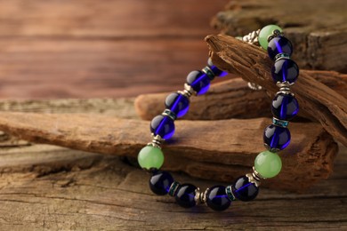 Stylish presentation of beautiful bracelet with gemstones on wooden table, closeup. Space for text