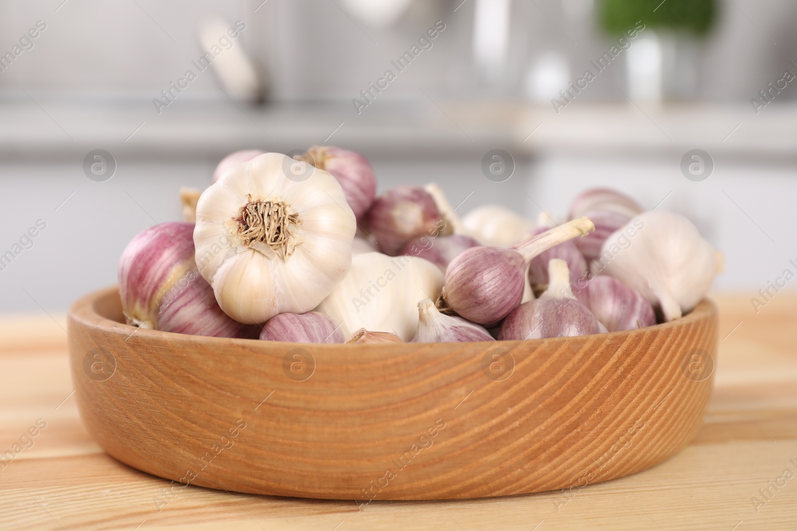 Photo of Bowl of fresh raw garlic on wooden table in kitchen, closeup
