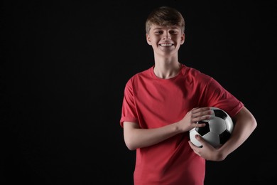 Teenage boy with soccer ball on black background. Space for text