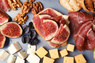 Photo of Sandwich with ripe fig and delicious products on grey background, top view