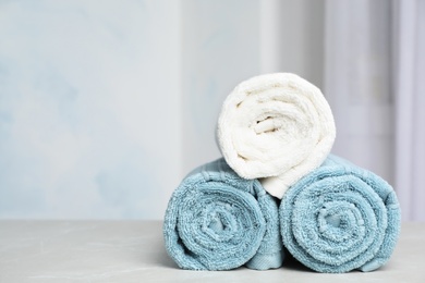 Rolled bath towels on table against blurred background. Space for text