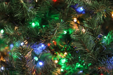 Photo of Christmas tree with bright string lights, closeup. Bokeh effect