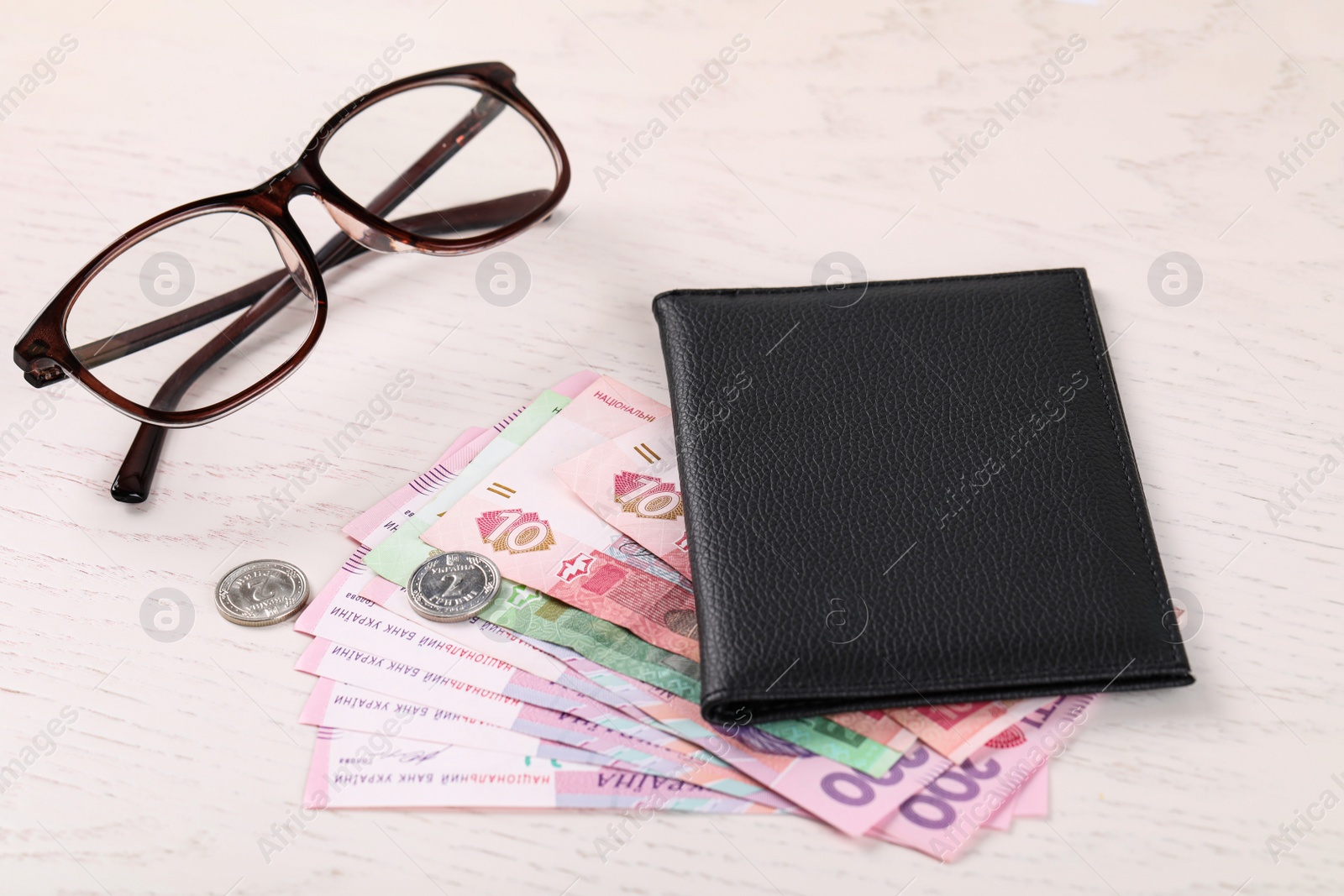 Photo of Pension certificate with Ukrainian money and glasses on white wooden background