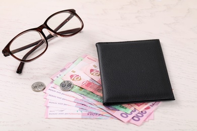 Photo of Pension certificate with Ukrainian money and glasses on white wooden background