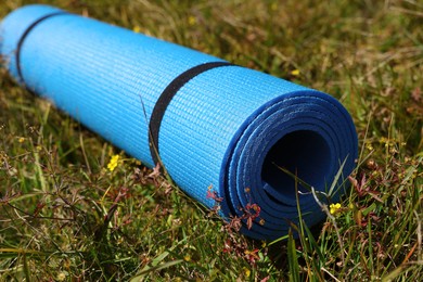 Rolled blue soft sleeping pad on grass, closeup