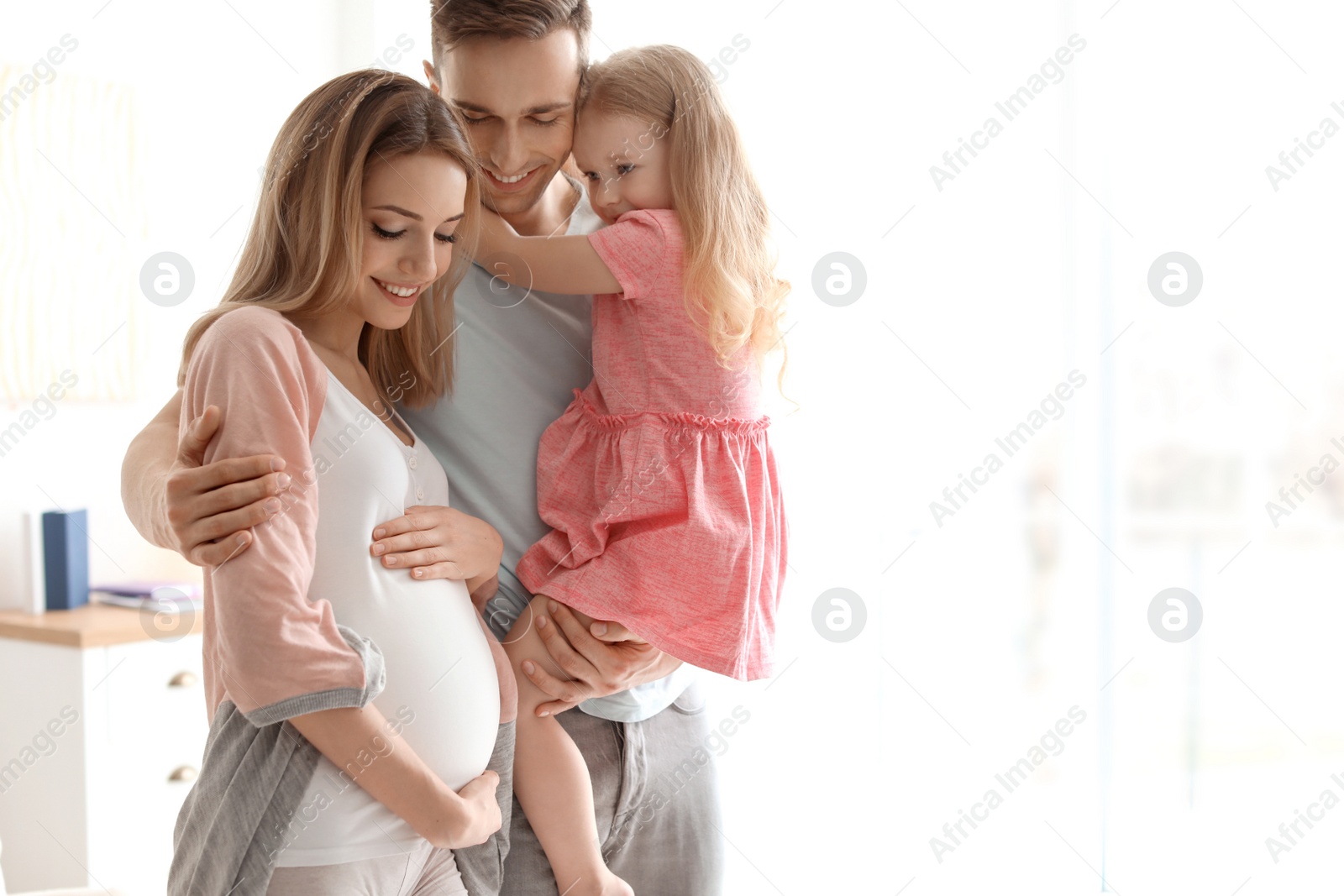 Photo of Young pregnant woman with her family at home