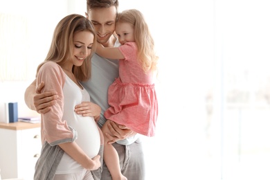 Photo of Young pregnant woman with her family at home