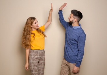 Happy young people celebrating victory on color background