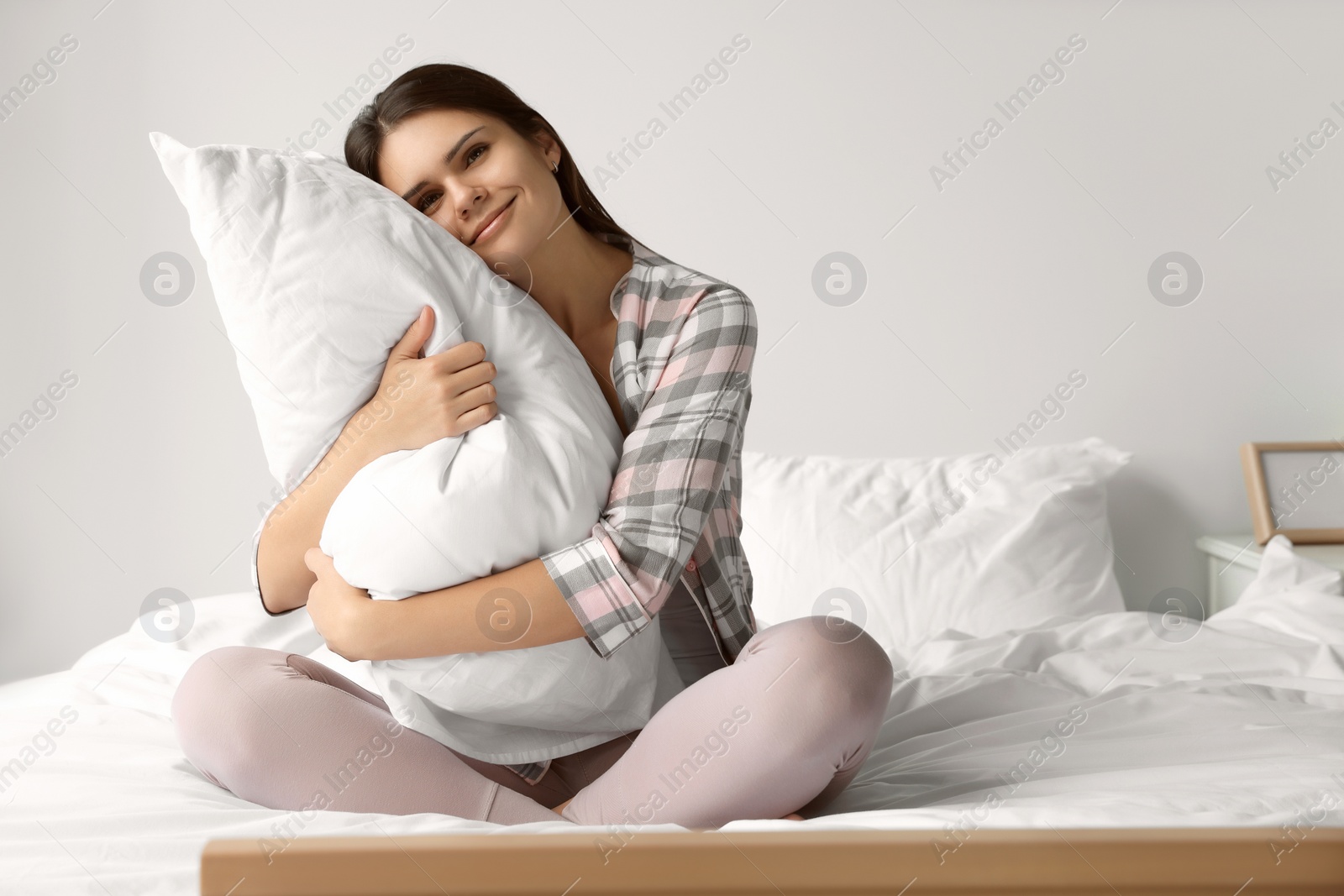 Photo of Beautiful young woman hugging pillow on bed at home