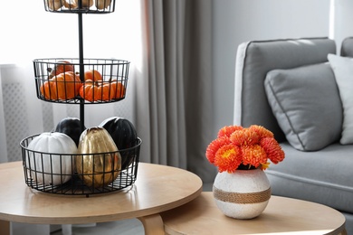 Photo of Vase with beautiful flowers and pumpkins on table in room. Interior design