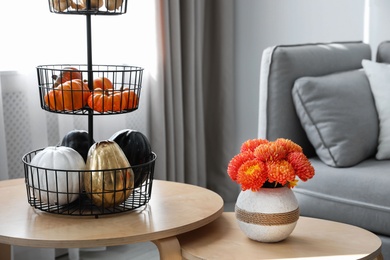 Vase with beautiful flowers and pumpkins on table in room. Interior design