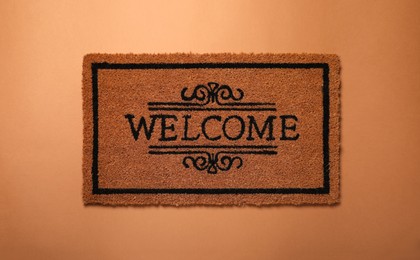 Doormat with word Welcome on brown background, top view