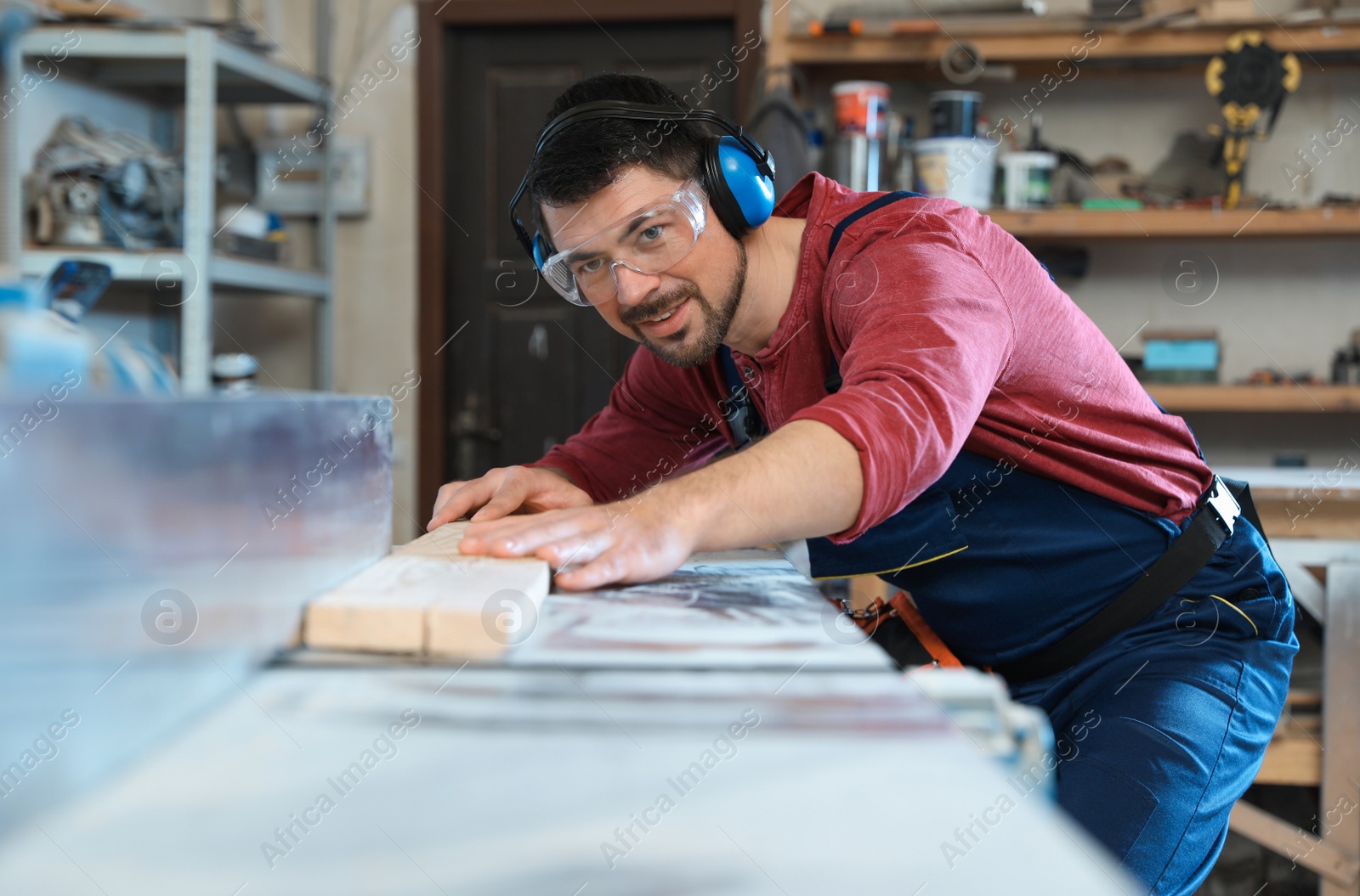 Photo of Mature man using wood working machine at carpentry shop