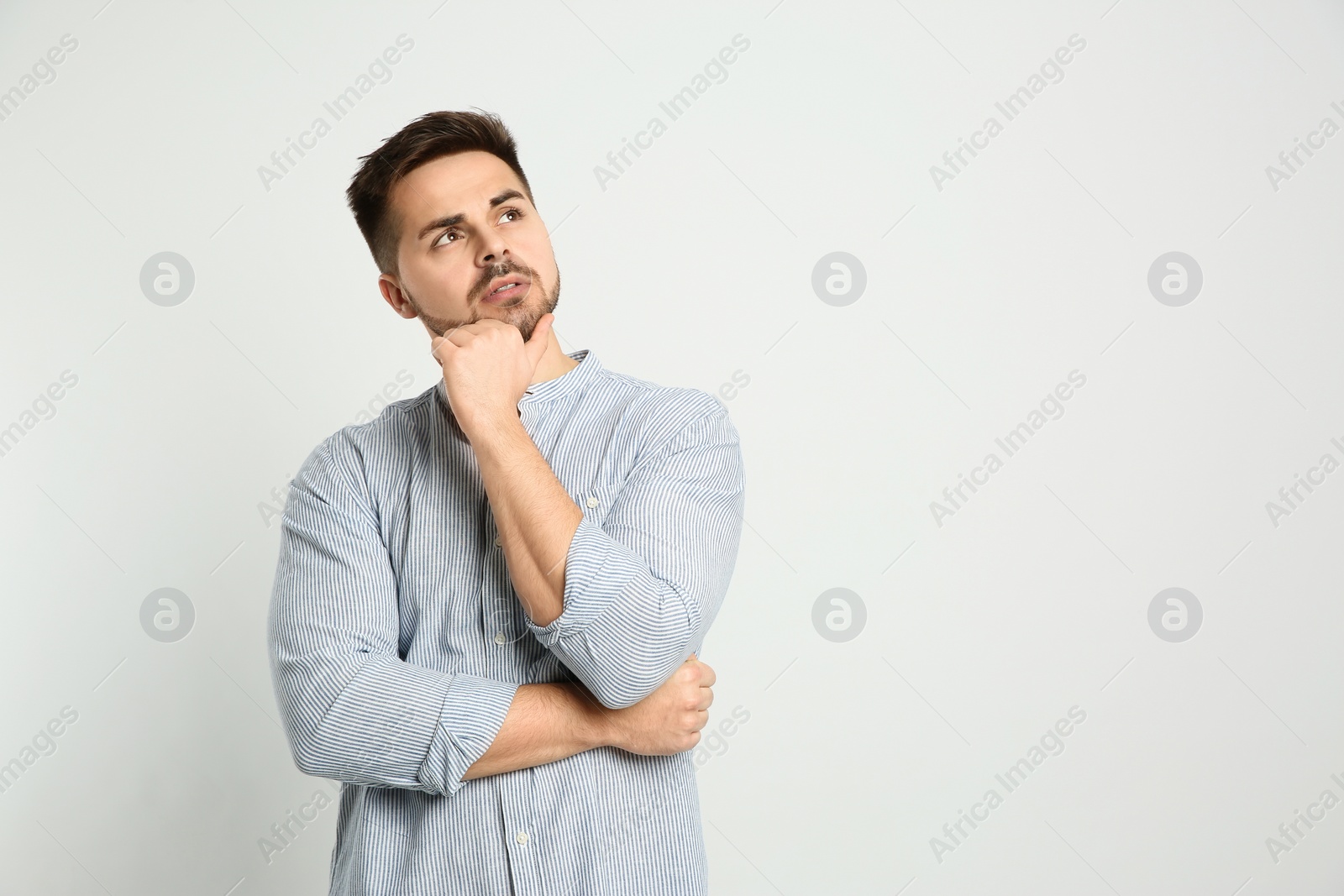 Photo of Pensive man on light background, space for text. Thinking about answer to question